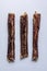 Three soft bully sticks. Dried beef esophagus Â  for pets. Vertical option. White background. Shooting from above. Macro.